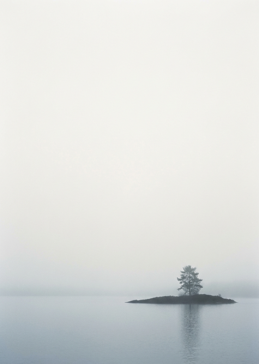 Vertikal minimalistisk naturposter som avbildar en dimmig ö på lugnt silverblått vatten med låg horisont.