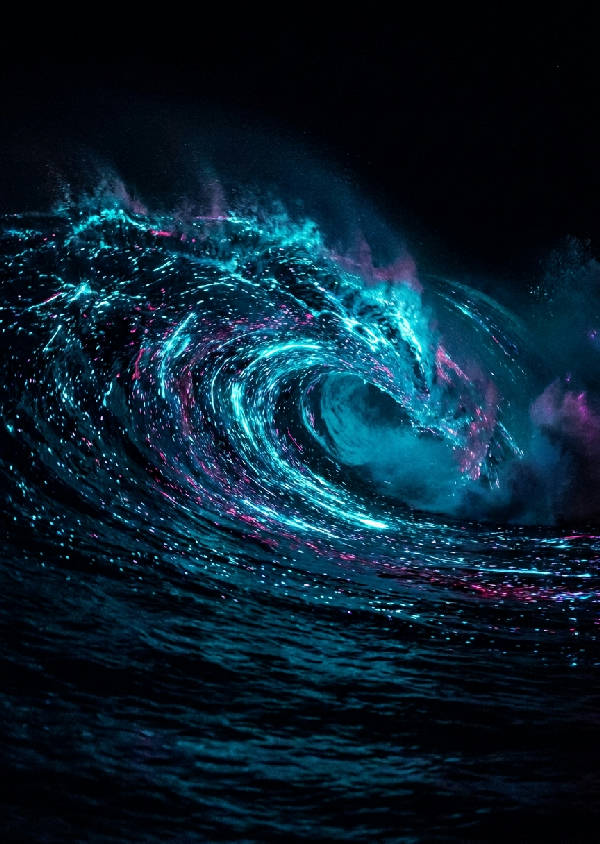 Långexponeringsfoto av en krusande havsbölja upplyst av självlysande plankton i elektriskt cyan och magenta.