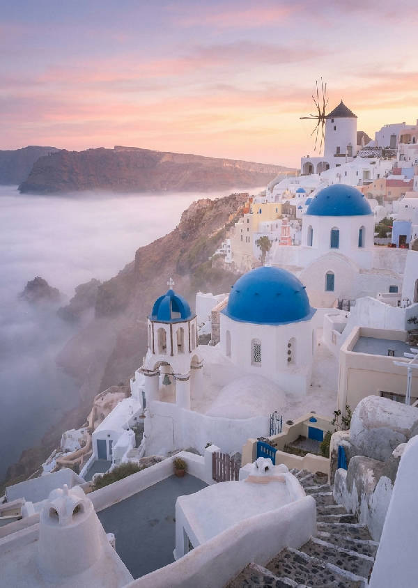 Hyperrealistiskt foto av Oia, Santorini, i morgondimma. Vita byggnader, blå kupoler, väderkvarn silhuett, soluppgång.