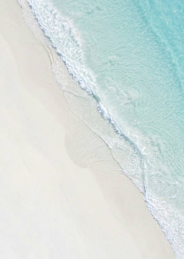 Flygfoto av turkosa havsvågor med vitt skum som bryter mjukt mot en sandstrand i vertikalt format.