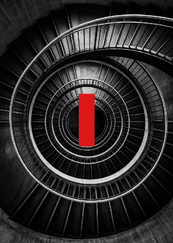 Fotografi av en spiralformad trappa i modern arkitektur, med framträdande röd accent och geometriska linjer. Porträttorientering.
