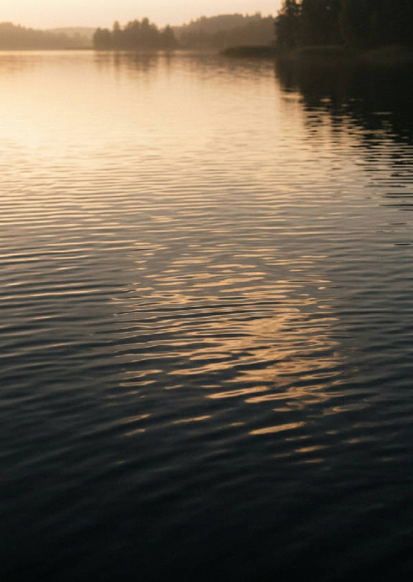 Närbild på mjuka, nästan transparenta krusningar på vattenytan, som bildar abstrakta mönster i lugna toner