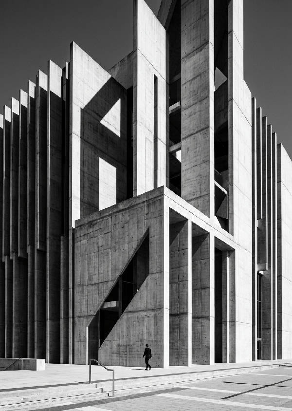 Svartvit fotografi av en arkitektonisk byggnad med dramatiska skuggor och rena linjer som framhävs