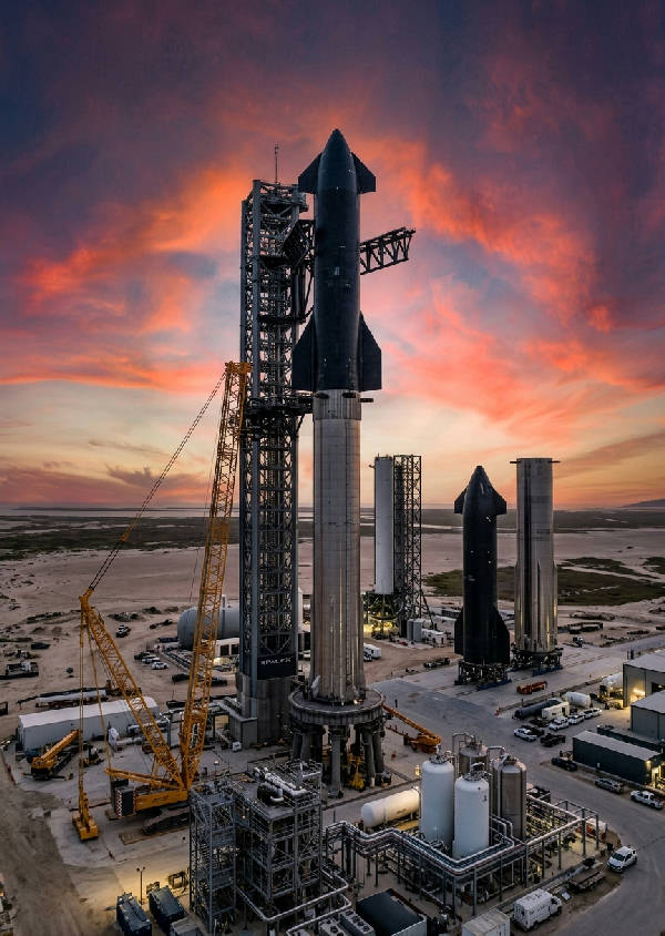 Detaljerad vertikal bild av en SpaceX-anläggning med raketdelar och industriella strukturer i blått ljus