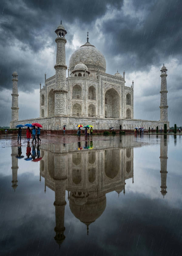 Hyperrealistiskt porträtt av Taj Mahal under ett kraftigt monsunregn, spegelbild i översvämmade floden, mörka moln, marmordetaljer glittrar av regndroppar, människor med färgglada paraplyer i förgrunden.