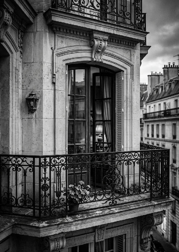 Svartvitt fotografi av en intrikat smidesjärnsbalkong på en byggnad i Paris