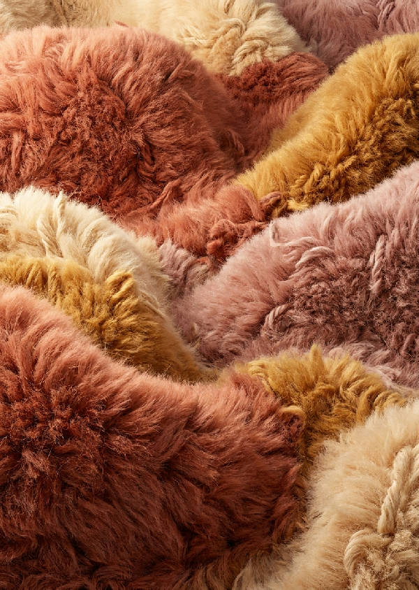 Extrem makrofotografi av ett tuftat garnlandskap med mjuka kullar och dalar i ull och sammet. Terracotta, dammrosa, ockra, krämvita färger.