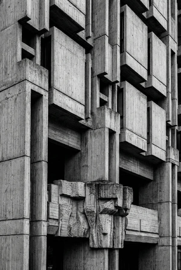 Närbild på en brutalistisk byggnad i svartvitt med skarpa linjer och betongtexturer i porträttformat