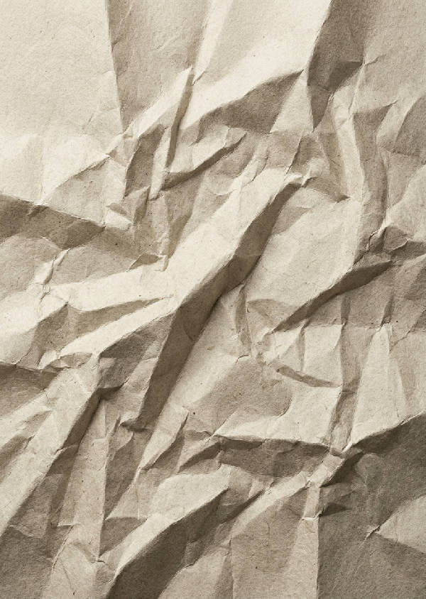 Närbild av ett stort papper med konstnärligt arrangerade veck och skrynklor i olika bruna och beige nyanser.