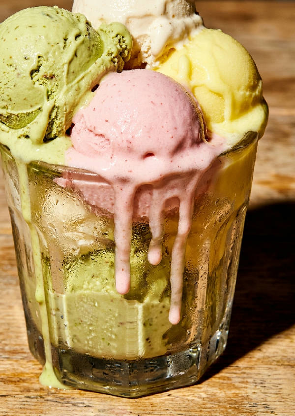 Närbild på smältande gelato i en vintage glasbägare med droppande texturer och kondens på glaset