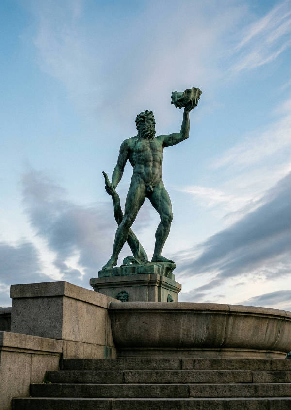 Låg vinkel foto av Carl Milles Poseidon-staty i Göteborg med tydlig, blekblå himmel