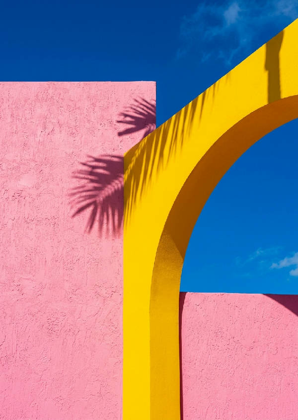 Vertikal bild av en byggnad med geometriska former i nyanser av lila, rosa och turkos, påminnande om Art Deco i Miami.